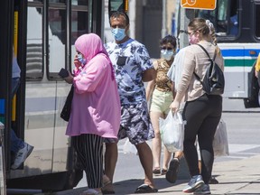 Citizens wearing masks board an LTC bus at the corner of Queens Avenue and Richmond Street in London. (Derek Ruttan/The London Free Press)