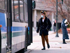 A man in a mask boards a bus on campus at Western University in London, Ontario on March 13, 2020. (Photo by GEOFF ROBINS/AFP via Getty Images)