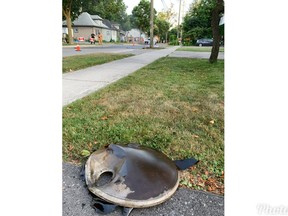 This hunk of metal, believed to be the lid of a transformer that exploded atop the hydro pole located at the centre-top of the frame, flew across two front yards in London's Blackfriars neighbourhood. Flames can be seen on the roadway under the pole. Photo taken Monday July 6, 2020. (Patrick Maloney/The London Free Press)