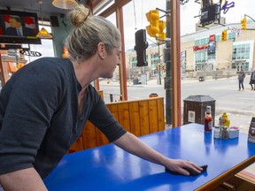 Mel Shymanski uses a bleached cloth to clean a table at JDee's, across from Budweiser Gardens, in March. Restaurants and bars across most of Ontario will be able to resume indoor service with physical distancing measures in place starting Friday, the province announced Monday, June 13. (Mike Hensen/The London Free Press)