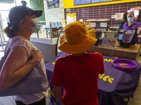 Maureen Campbell and her son Benjamin Daabous, 12, order drinks at Booster Juice on Wonderland Road with manager Valerie Balcarras behind the till. Alll are wearing medical masks to slow COVID-19's spread. Photograph taken on Thursday July 2, 2020. (Mike Hensen/The London Free Press)