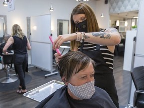 Hair stylist Blaney Hanley works on Barb Elliott at the Groove Hair Lounge in Sherwood Forest Mall in London. Staff and customers at hair salons and personal service environments that require close contact are required to wear masks since the province allowed them to reopen last month. (Mike Hensen/The London Free Press)