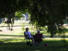 Two women sit in the deep shade in Springbank Park. (Mike Hensen/The London Free Press)