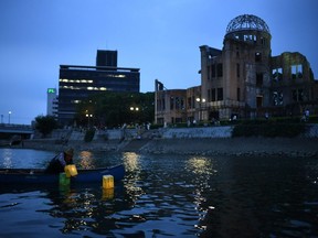 A volunteer releases paper lanterns on Motoyasu River in front of ruins of the Hiroshima Prefectural Industrial Promotion Hall, now the atomic bomb dome, in Hiroshima on Thursday, marking 75 years since the world's first atomic bomb attack. (Philip Fong/AFP via Getty Images)
