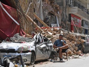A Lebanese man talks on the phone while seated by the rubble of a destroyed traditional building in the Gemmayzeh neighbourhood, on August 12, 2020, following last week's cataclysmic port explosion which devastated the capital Beirut. (Photo by - / AFP) (Photo by -/AFP via Getty Images)