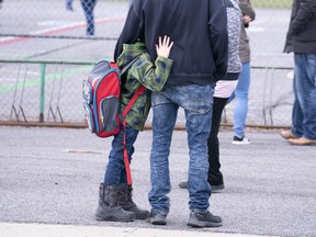 A boy hugs his father as he waits to be called to enter the schoolyard at Marie-Derome School in Saint-Jean-sur-Richelieu, Que., as schools in that province reopened in May. Plans are being made across the country for how to safely send students back to school in the fall as the COVID-19 pandemic continues. (Paul Chiasson/The Canadian Press)