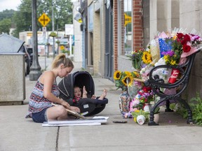 With seven-month-old daughter Abigail at her side, Destiny Fick fills a frame with photos of her cousin Ashten Elizabeth Fick before adding it to a memorial for the mother-of-three on Thames Street in Ingersoll on Sunday August 2, 2020. Ashten was struck and killed by a transport truck as she crossed the street while pushing a stroller on Friday. Derek Ruttan/The London Free Press/Postmedia Network
