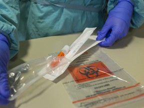 A sleeve containing a COVID-19 swab and container is opened at the Oakridge COVID-19 assessment centre. (Mike Hensen/The London Free Press)