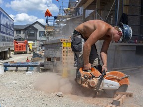 Zach Parkins of Griffin Masonry cuts a brick to size as they work on a series of townhouses north of Sunningdale Road in London.  Photograph taken on Thursday August 6, 2020.  Mike Hensen/The London Free Press