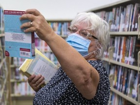 Sally Meade of London checks out a possibility at the Beacock Branch of the London Public Library on Huron Street in London, Ont.  (Mike Hensen/The London Free Press)