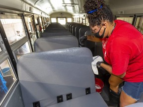 Catrina Stoute of Elgie Bus Lines in London cleans a bus inside and out Monday to get it ready for the new school year. Drivers will wear face shields and spray  down commonly touched hard surfaces such as the tops of seats and railings. (Mike Hensen/The London Free Press)