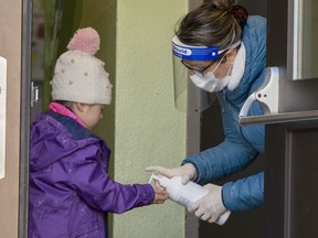 Pupils get their hands sanitized as they head to school in St-Sauveur, Que., on May 11. Similar scenes will play out when Quebec's COVID-shuttered schools reopen Aug. 31.