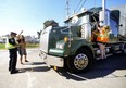 An activist is ticketed for holding up a livestock transport truck at the Sofina Fearmans Pork processing plant in Burlington last month. On Monday, the province announced a new law that makes it an offence to “stop, obstruct, hinder or otherwise interfere with a motor vehicle transporting farm animals." (Diana Martin, Postmedia Network)