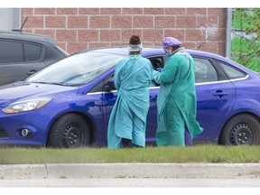 Health care workers assess a person at the Carling Heights Optimist Community Centre COVID-19 assessment centre  in London, Ont. on Monday May 4, 2020. Derek Ruttan/The London Free Press/Postmedia Network