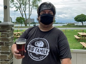 Server Dave Evans delivers an Irish red ale balanced with notes of soft caramel and fruit on the riverfront patio of Big Family Brewing in Sarnia.
(Barbara Taylor/The London Free Press)