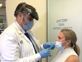 Shoppers Drug Mart owner/pharmacist Nick Vander Gulik shows how a COVID-19 test is performed on Pharmacy manager Ashley Nethercott. (MIKE HENSEN, The London Free Press)