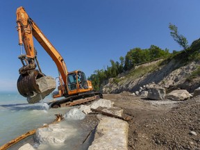Cody Rahn of Huron District Contracting moves a boulder that will form part of a barrier against record-high water levels on the shoreline of Lake Huron just north of Bayfield on Tuesday. (Mike Hensen/The London Free Press)