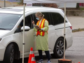 A staff member takes information at the COVID-19 screening centre at Oakridge arena in London. About 15 city employees are helping staff at the Middlesex-London Health Unit with contact tracing when after people test positive.  (Mike Hensen/The London Free Press)