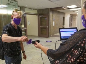 Dillon Byn swipes his student card for Melodie Gruendler before entering an engineering class at Western University.  Mike Hensen/The London Free Press