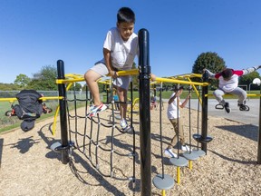 William Moo, 10, of Lord Elgin Public School climbs a rope wall, part of the new playground equipment installed at the school. Mike Hensen/The London Free Press
