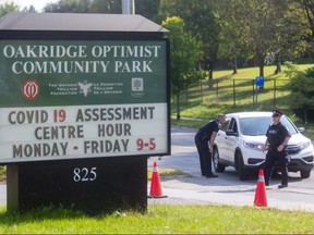 London police Sgt. Mark Elgersma and Const. Steve Daley were on hand Friday to tell motorists that the the Oakridge Arena COVID-19 assessment centre had reached capacity for the day.  (Mike Hensen/The London Free Press)
