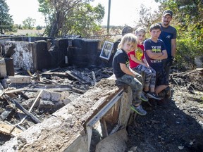 Justin Whitney with three of his six children, J.D., 3, Trent, 7, and Kayden, 10, visit the site of their former home, which burned down last week near Dutton. (Derek Ruttan/The London Free Press)