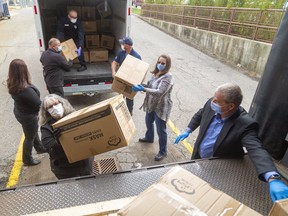 Lorrie Forbes and Brian Duivesteyn of Presstran help unload boxes of masks at St. Thomas-Elgin General Hospital. 
Presstran and Formet, both Magna International companies, donated 50,000 medical-grade masks to the hospital on Friday. (Mike Hensen/The London Free Press)