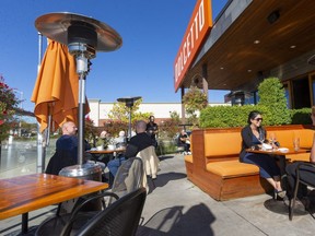 Shelley Vinayak and Lissa Savage have lunch on the patio at Dolcetto on Southdale Road. Like many restaurants, Dolcetto is using natural gas heaters to extend outdoor dining into the colder months. (Mike Hensen/The London Free Press)