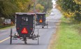 Horse-drawn buggies travel along on a country road northeast of Aylmer. The slow-moving wooden buggies are a poor match for a modern truck or automobile if they are involved in a collision, but the province has no plans to change regulations regarding them. (Mike Hensen/The London Free Press)