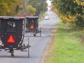 Horse-drawn buggies travel along on a country road northeast of Aylmer. The slow-moving wooden buggies are a poor match for a modern truck or automobile if they are involved in a collision, but the province has no plans to change regulations regarding them. (Mike Hensen/The London Free Press)
