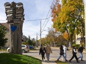 Western University students walk by the old stump at the intersection of John and St. George streets, which shows distances for places around the world.  (Mike Hensen/The London Free Press)