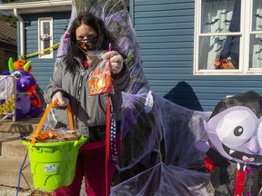 Crystal Smitjes shows how she plans to give out candies on Halloween with the candies bagged up while wearing a mask and gloves. (Mike Hensen/The London Free Press)