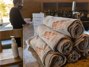 Hostess Hanna Peters with blankets available for sale at Dolcetto on Southdale Road, for customers who get cold on the patio in London, Ont. (Mike Hensen/The London Free Press)