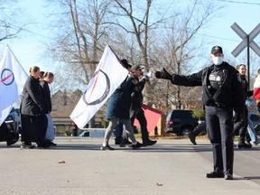 A police officer directs traffic while anti-restrictions demonstrators march to Veterans Memorial Gardens in St. Thomas during a protest earlier this month. St. Thomas police intend to charge two organizers of the Nov. 14 demonstration. (DALE CARRUTHERS/The London Free Press)