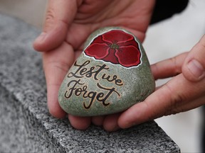 Julie Mungall places her painted stones at the Brookside veterans cemetery in Winnipeg, Oct. 24, 2020.