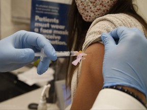 A pharmacist administers the flu shot at a Shoppers Drug Mart.