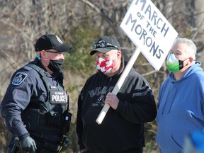 A St. Thomas police officer speaks with counter-demonstrators at the St. Thomas Elgin Memorial Centre, where around 200 protesters gathered on Saturday to rally against public-health restrictions put in place to slow COVID-19's spread. (Dale Carruthers/The London Free Press)