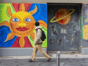 Jesse Tremain looks into the eyes of the sun (it's where the fun is, after all) featured on one the of several murals by Rich Denomme gracing the exteriors of businesses in downtown London. (Derek Ruttan/The London Free Press)