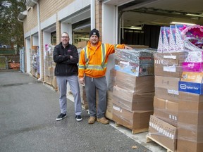 Southside Group property manager Jeff Brown, left, and crew leader Darren Vyfschaft pose with skids of Christmas gifts for children that they will be donating to a variety of charities in London. (Derek Ruttan/The London Free Press)