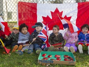 Children from the Western Day Care wave flags in front of a Canadian flag and their box of poppy rocks, as they await a visit Wednesday from veteran Ron Stewart, who for years has helped the day care kids learn about Remembrance Day by having the children visit a small cenotaph at the Church of the Epiphany on Briscoe Street West in London. (Mike Hensen/The London Free Press)