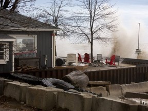 Elvis Garcia and his wife Marta Jurys watch from their front room as their cottage is sprayed by windswept water as massive waves pound up against their cottage's retaining wall on Lake Erie in Port Bruce. (Mike Hensen/The London Free Press)