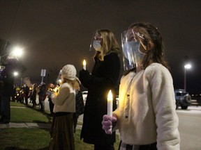 Maren Davidson, 8, holds a candle while joining a mass carolling event outside the Village on the St. Clair in Sarnia. It was part of The Christmas Ribbon, a project of the Nightingale Chorus.