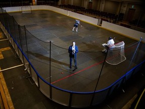 Brad Jones, president of Jones Entertainment Group, stands in ball hockey rink built inside Centennial Hall in London, while Hokey Langan takes shots on Jared Vine on Wednesday. Jones Entertainment, which manages the city-owned concert venue, converted it into a rink with advice from the Middlesex-London Health Unit to adhere to COVID-19 safety precautions. (Derek Ruttan/The London Free Press)