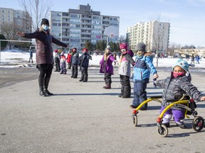 Madame Trinka Psellas instructs her grade one students to put up their airplane wings to ensure they are socially distanced while lining up to enter Louise Arbour French Immersion Public School after morning recess in London, Ont. on Thursday December 3, 2020. (Derek Ruttan/The London Free Press)