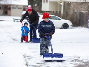 Three year old Roman Gagnon helps out his dad Jacoub and 23-month-old brother Malcolm shovel snow from the sidewalk in front of their home in London. (Derek Ruttan/The London Free Press)