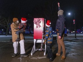 Jesse Foster raises his arm after his son Henry, 8 Foster symbolically turned on the lights in Victoria Park with his mom Brooke Thompson and little brother Forest, 3 Foster in London, Ont.  Jesse works for LHSC Victoria Campus. Photograph taken on Thursday December 3, 2020. (Mike Hensen/The London Free Press)
