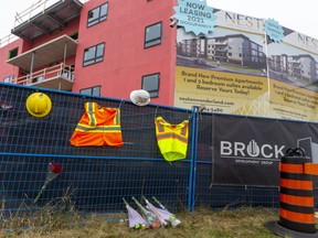 On the construction fencing at 555 Teeple Terrace, two hard hats and two safety vests and bouquets of flowers have been placed as a memorial for the two men who died. (Mike Hensen/The London Free Press)