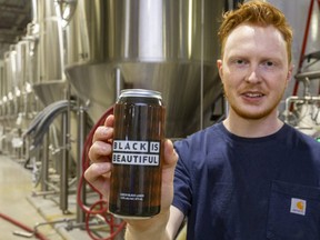Matt Cummings, brewery manager for Equals Brewing Company in London, holds up their new beer, a Czech black lager called Black is Beautiful. (Mike Hensen/The London Free Press)
