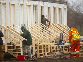 Workers were busy Tuesday at the site of a new temporary homeless shelter being put together on Elizabeth Street in London. Four trailers have been subdivided into 30 rooms and three large trailers have been combined to make a common area. (Mike Hensen/The London Free Press)