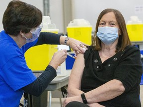 Karen Dann, an administrator at a local long-term care home, on Wednesday was given the very first COVID-19 vaccine in London. It was administered by public health nurse Tracy Benedict at the city's field hospital, set up at Western Fair. (Mike Hensen/The London Free Press)